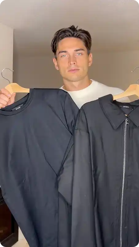 Person holding black shirt and jacket on hangers