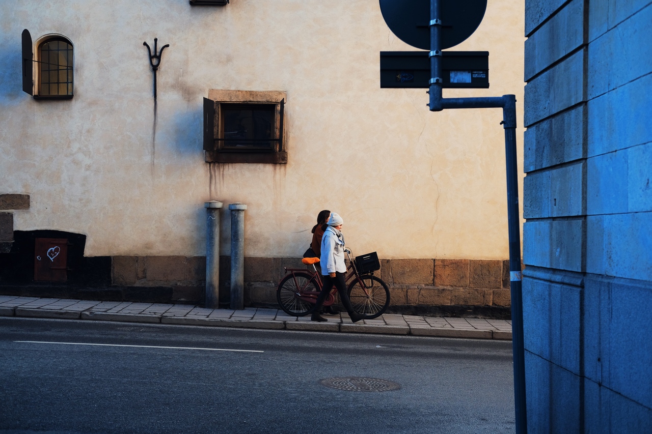 Two women walking a bike through an alley in Stockholm.