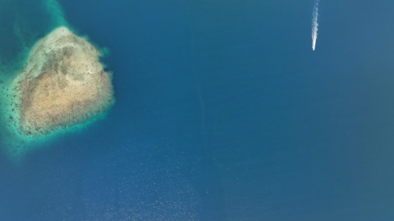 Aerial view by drone, Raiatea, motorboat in the lagoon, UHD 4K