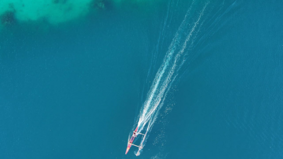 Outrigger Canoe sailing on Tahaa Lagoon, Drone aerial view of turquoise water, Vanilla Island, French Polynesia