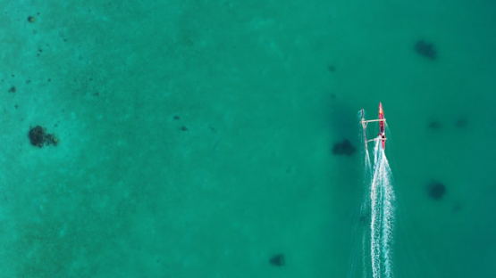 Outrigger Canoe sailing on Tahaa Lagoon, Drone aerial view of turquoise water, Vanilla Island, French Polynesia