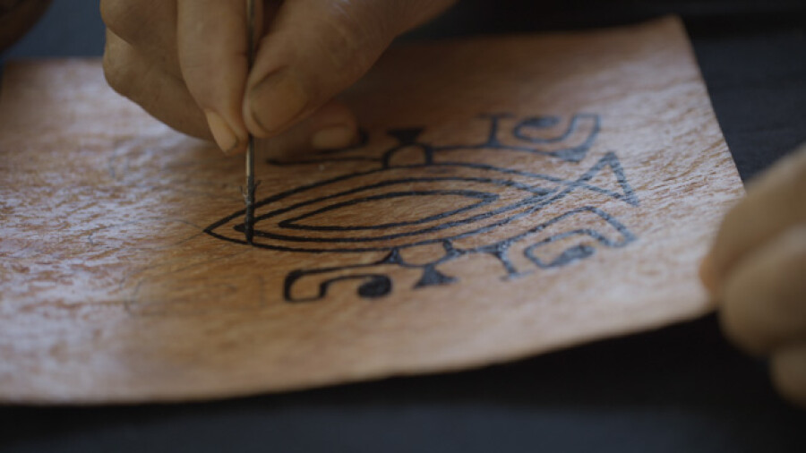 Marquesan woman painting traditional tapa cloth