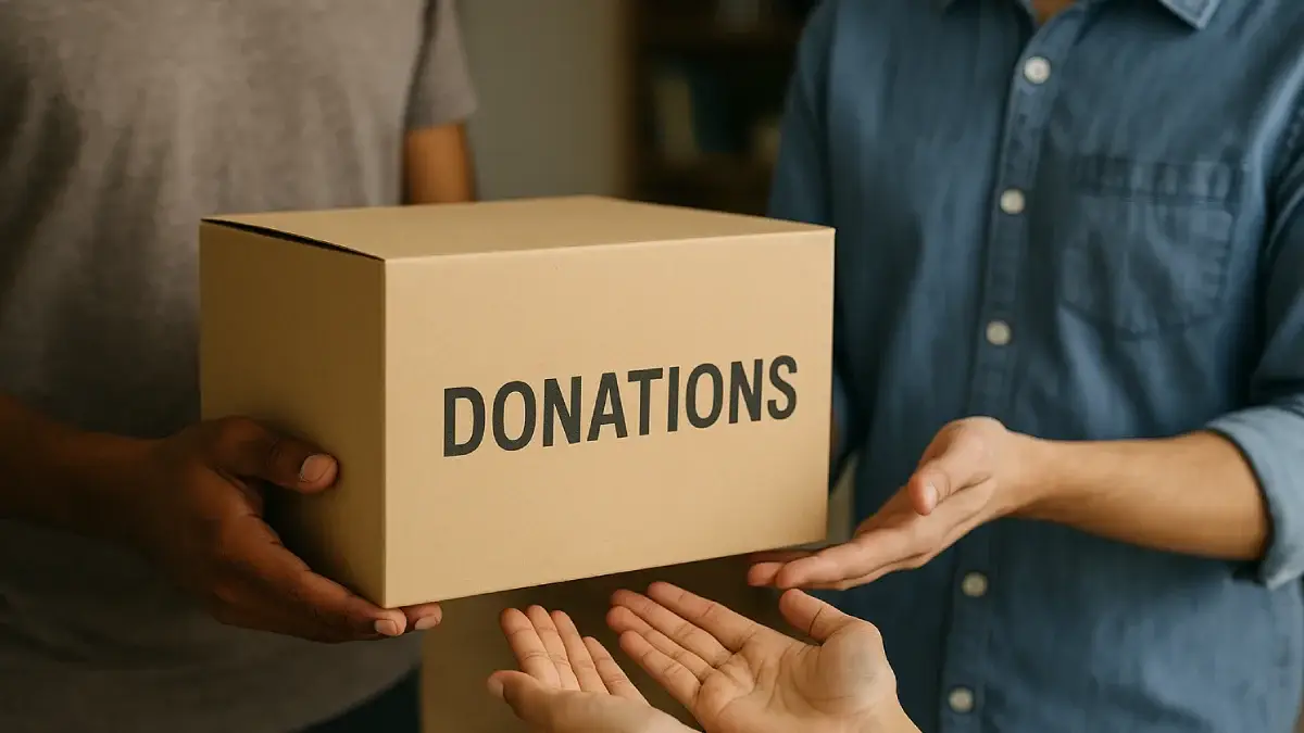 Seorang tangan menyerahkan kotak kardus bertuliskan "DONATIONS" kepada tangan lain, mewakili etika donasi yang berfokus pada transparansi dan tanggung jawab dalam memberikan bantuan.